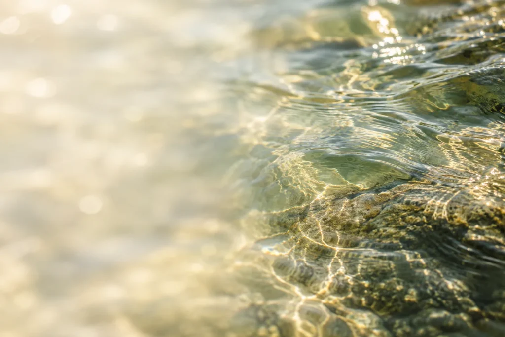 Sanfte sich kreuzende Wasserwellen mit goldenen Lichtreflexen.