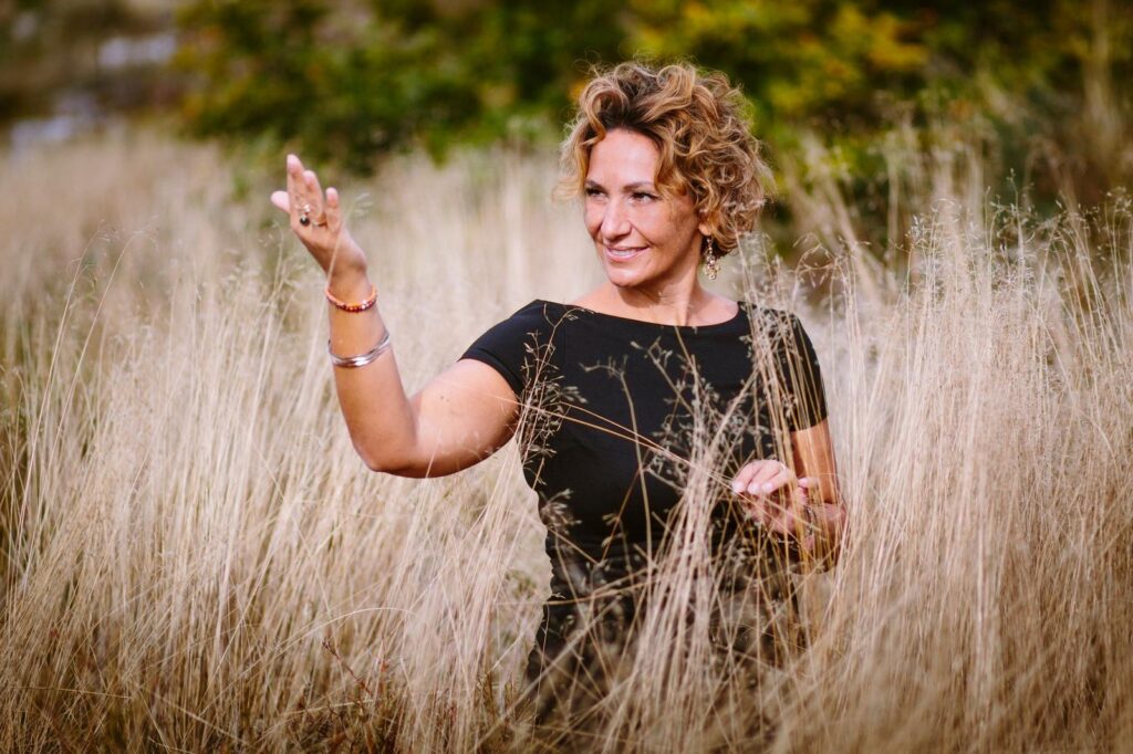 Ursula Karaca mit erhobener Hand im hohen Gras